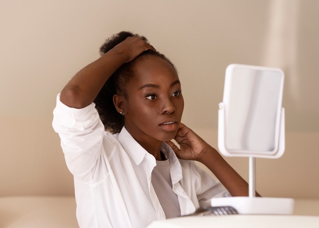 Photo gratuite vue latérale femme coiffant les cheveux