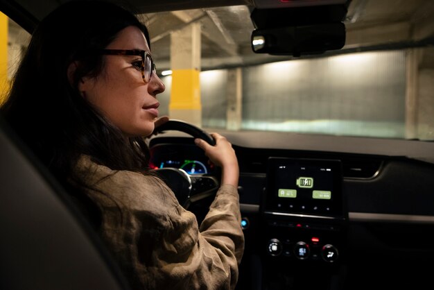 Vue latérale femme conduisant une voiture électrique