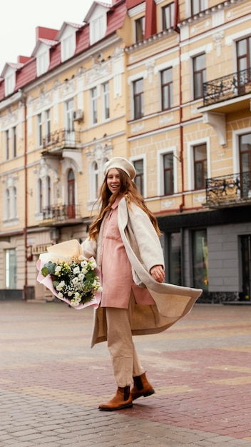 Vue latérale d'une femme élégante à l'extérieur tenant un bouquet de fleurs au printemps