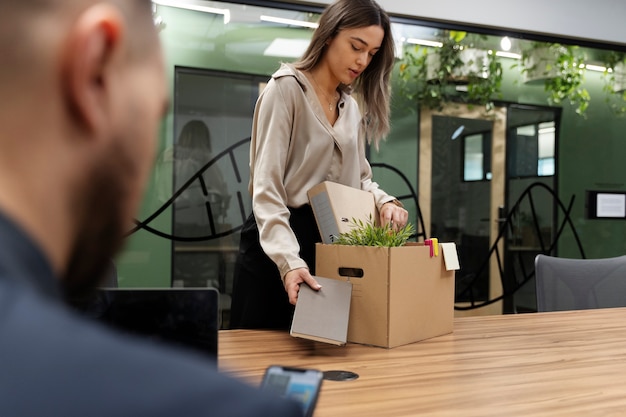 Vue latérale femme emballant des articles de bureau