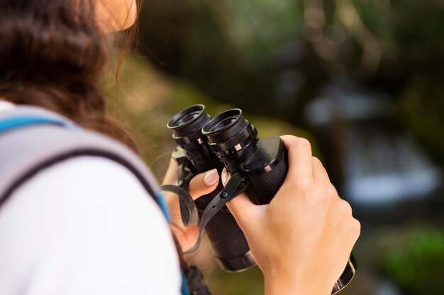 Vue latérale d'une femme explorant la nature avec des jumelles