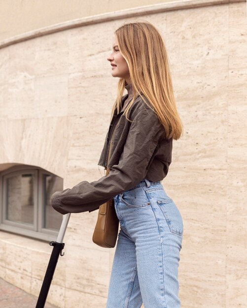 Vue latérale de la femme à l'extérieur avec scooter électrique