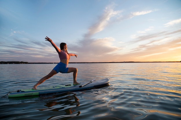 Vue latérale femme faisant du yoga sur paddleboard