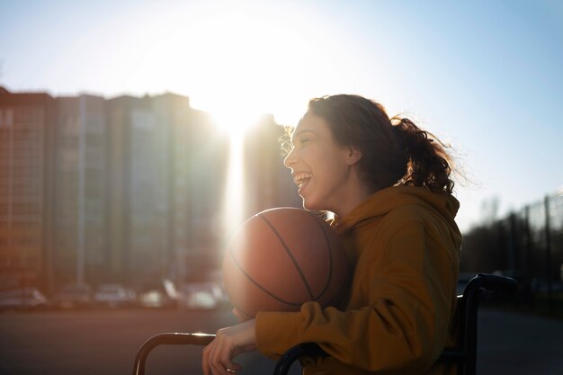 Vue latérale femme en fauteuil roulant jouant au basketball