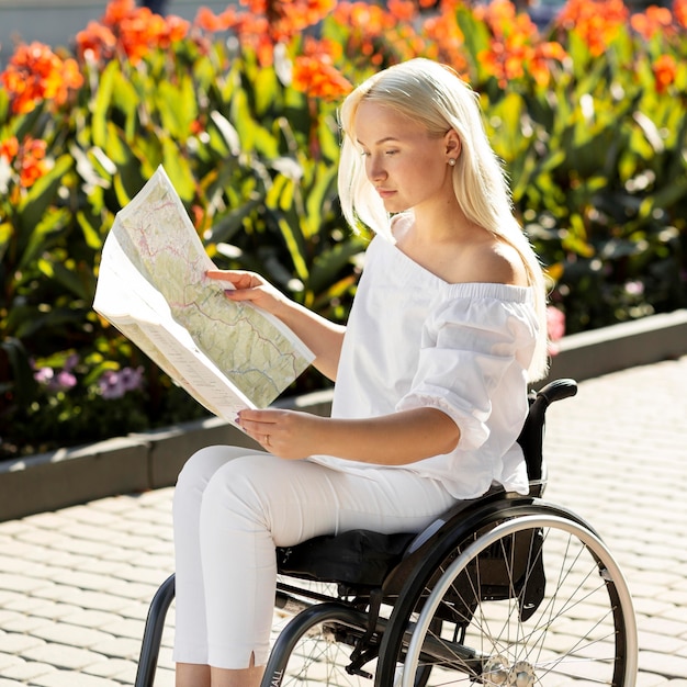 Photo gratuite vue latérale de la femme en fauteuil roulant en regardant la carte à l'extérieur