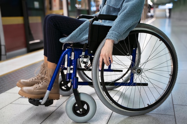 Vue latérale femme en fauteuil roulant à la station de métro