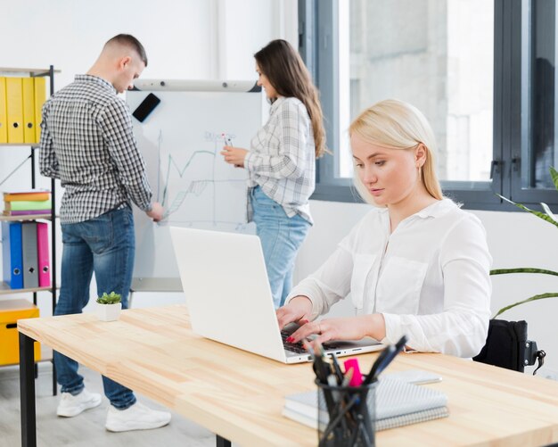 Vue latérale d'une femme en fauteuil roulant travaillant au bureau