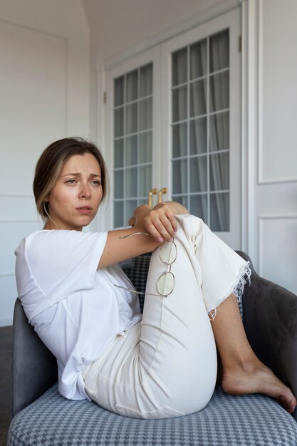 Vue latérale femme inquiète assise sur une chaise