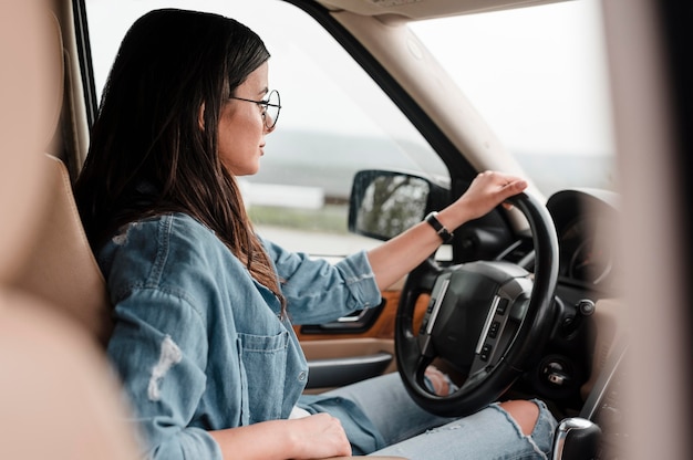 Photo gratuite vue latérale de la femme avec des lunettes voyageant seul en voiture