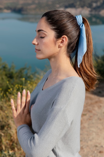 Vue latérale femme méditant dans la nature