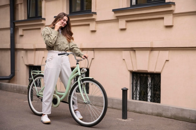 Vue latérale d'une femme parlant au téléphone tout en faisant du vélo