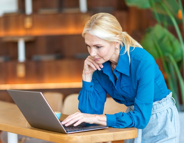 Photo gratuite vue latérale d'une femme plus âgée travaillant tout en prenant un café