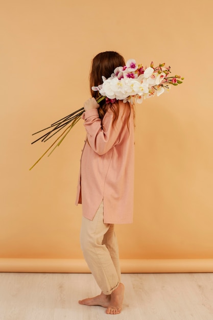 Vue latérale d'une femme posant avec beau bouquet de fleurs de printemps