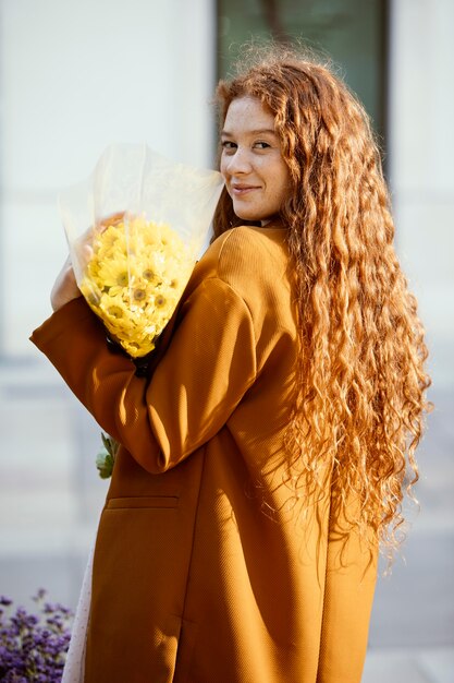 Vue latérale d'une femme posant à l'extérieur avec bouquet de fleurs de printemps