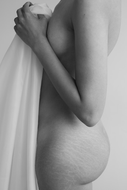 Vue latérale femme posant nue avec un chiffon
