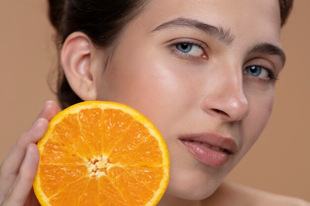 Vue latérale femme posant avec une tranche d'orange