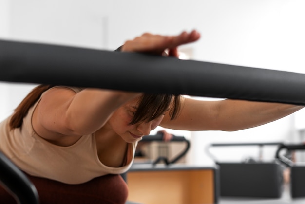 Photo gratuite vue latérale d'une femme prenant un cours de réformateur de pilates