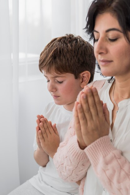 Vue latérale d'une femme priant avec son enfant