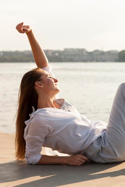 Vue latérale d'une femme profitant du soleil au bord du lac