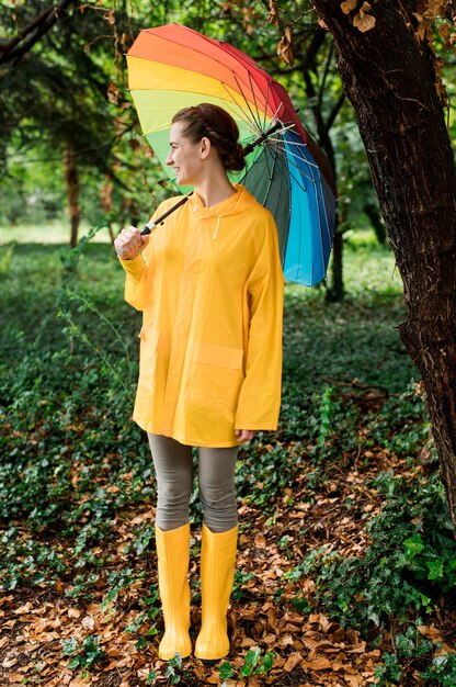 Vue latérale femme regardant ailleurs tout en tenant un parapluie