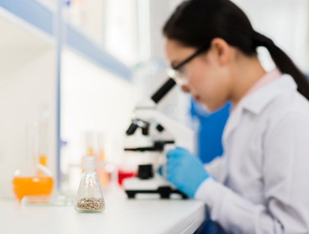 Vue latérale d'une femme scientifique défocalisée avec microscope