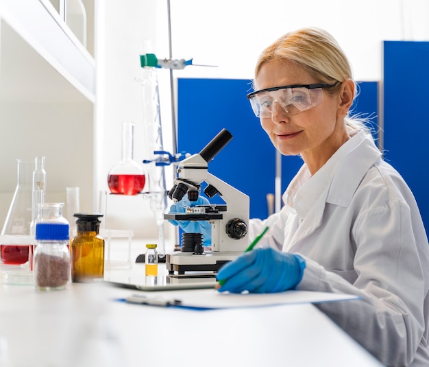 Vue latérale d'une femme scientifique avec des gants chirurgicaux en laboratoire