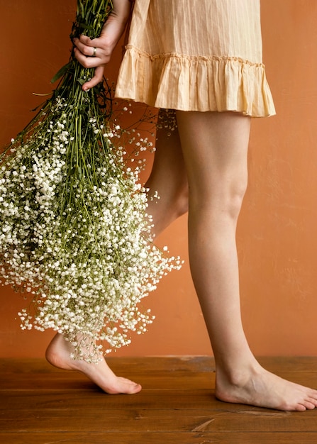 Vue latérale d'une femme séduisante posant tout en tenant le bouquet de fleurs de printemps