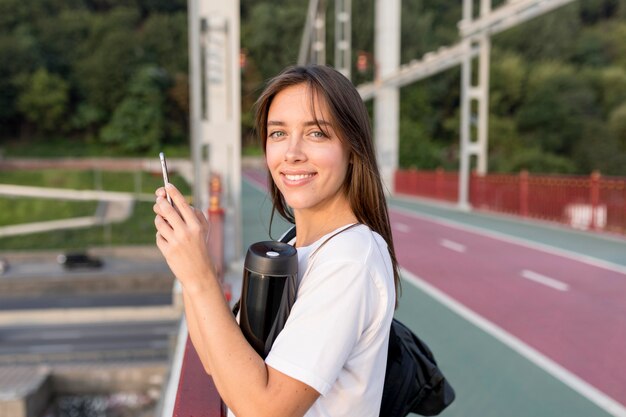 Vue latérale de la femme avec smartphone sur le pont lors d'un voyage