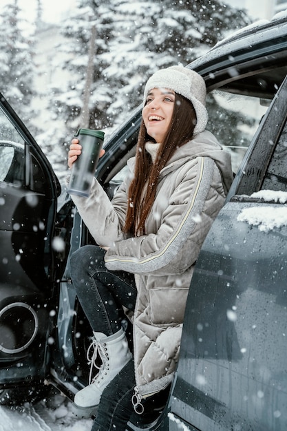 Vue latérale d'une femme souriante appréciant la neige lors d'un road trip