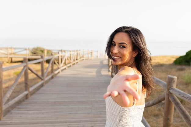 Vue latérale d'une femme souriante posant à l'extérieur avec la main pour atteindre