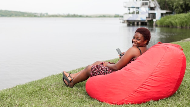 Photo gratuite vue latérale d'une femme souriante sur un sac de haricots se détendre à l'extérieur