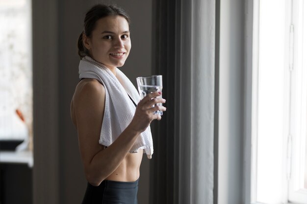 Vue latérale d'une femme souriante et tenant un verre d'eau