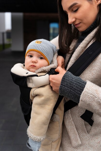 Vue latérale femme tenant bébé dans le porte-bébé