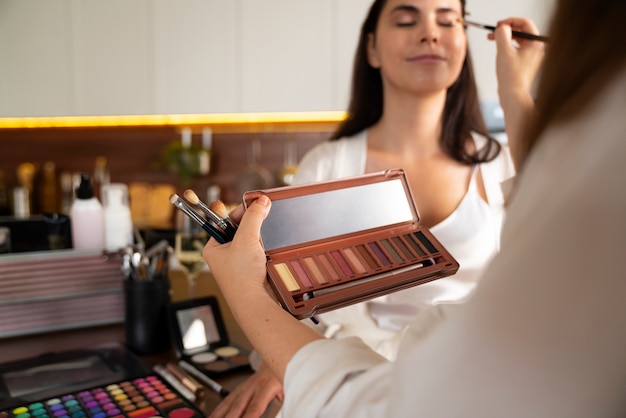 Vue latérale femme tenant une palette d'ombres à paupières