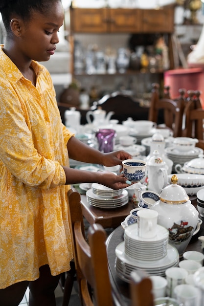 Vue latérale femme tenant une tasse au magasin d'antiquités