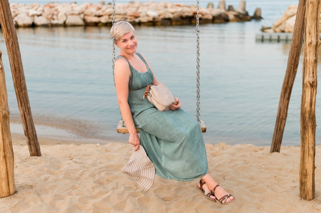Photo gratuite vue latérale de la femme de tourisme senior dans la balançoire sur la plage