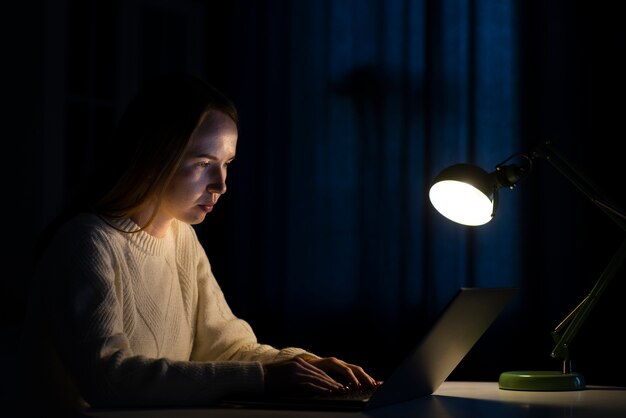 Vue latérale d'une femme travaillant sur un ordinateur portable