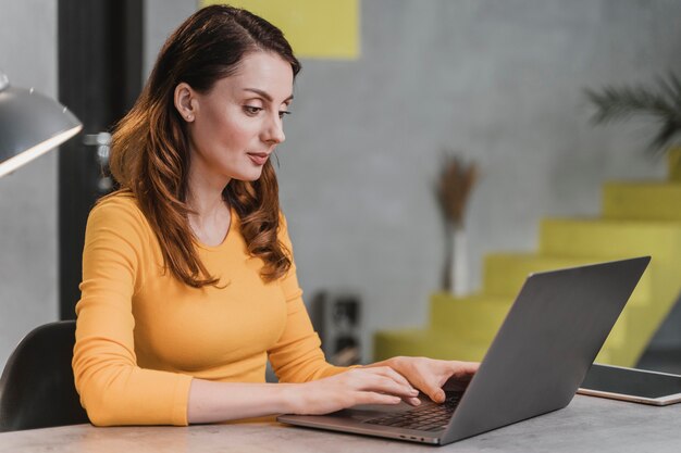 Vue latérale femme travaillant sur ordinateur portable