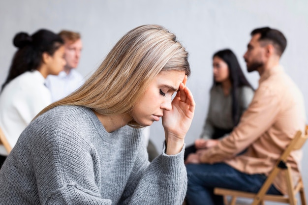 Vue latérale d'une femme triste lors d'une séance de thérapie de groupe