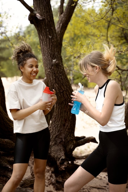 Vue latérale des femmes souriantes avec des bouteilles d'eau