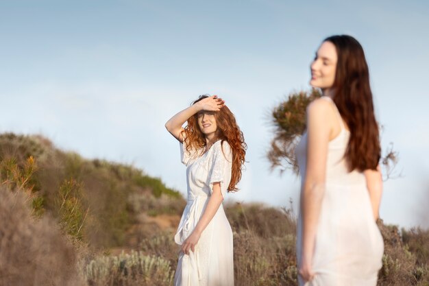 Vue latérale des femmes souriantes portant des robes blanches