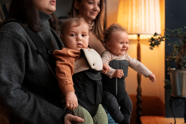 Vue latérale des femmes tenant des bébés dans des porte-bébés