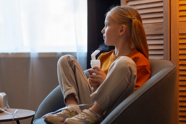 Photo gratuite vue latérale fille à l'aide d'un nébuliseur