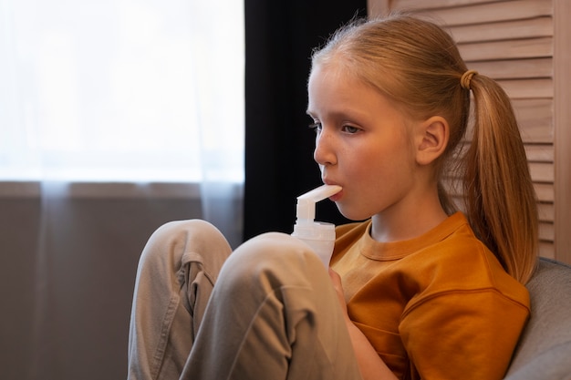 Photo gratuite vue latérale fille à l'aide d'un nébuliseur