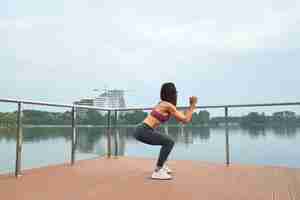 Photo gratuite vue latérale d'une fille athlétique faisant des exercices de squat en plein air