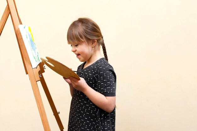 Vue latérale d'une fille heureuse avec la peinture du syndrome de Down