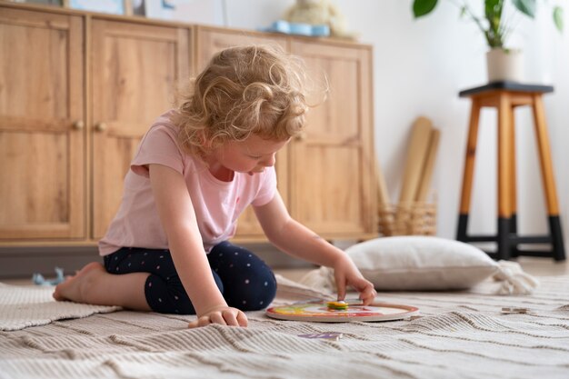 Vue latérale fille jouant sur le sol avec puzzle