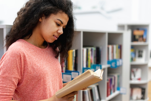 Photo gratuite vue latérale fille à la lecture de la bibliothèque