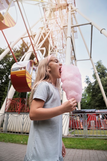 Photo gratuite vue latérale fille mangeant de la barbe à papa