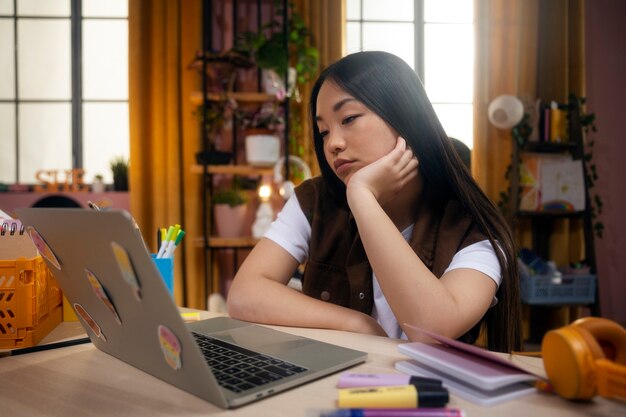 Vue latérale fille avec ordinateur portable à la maison